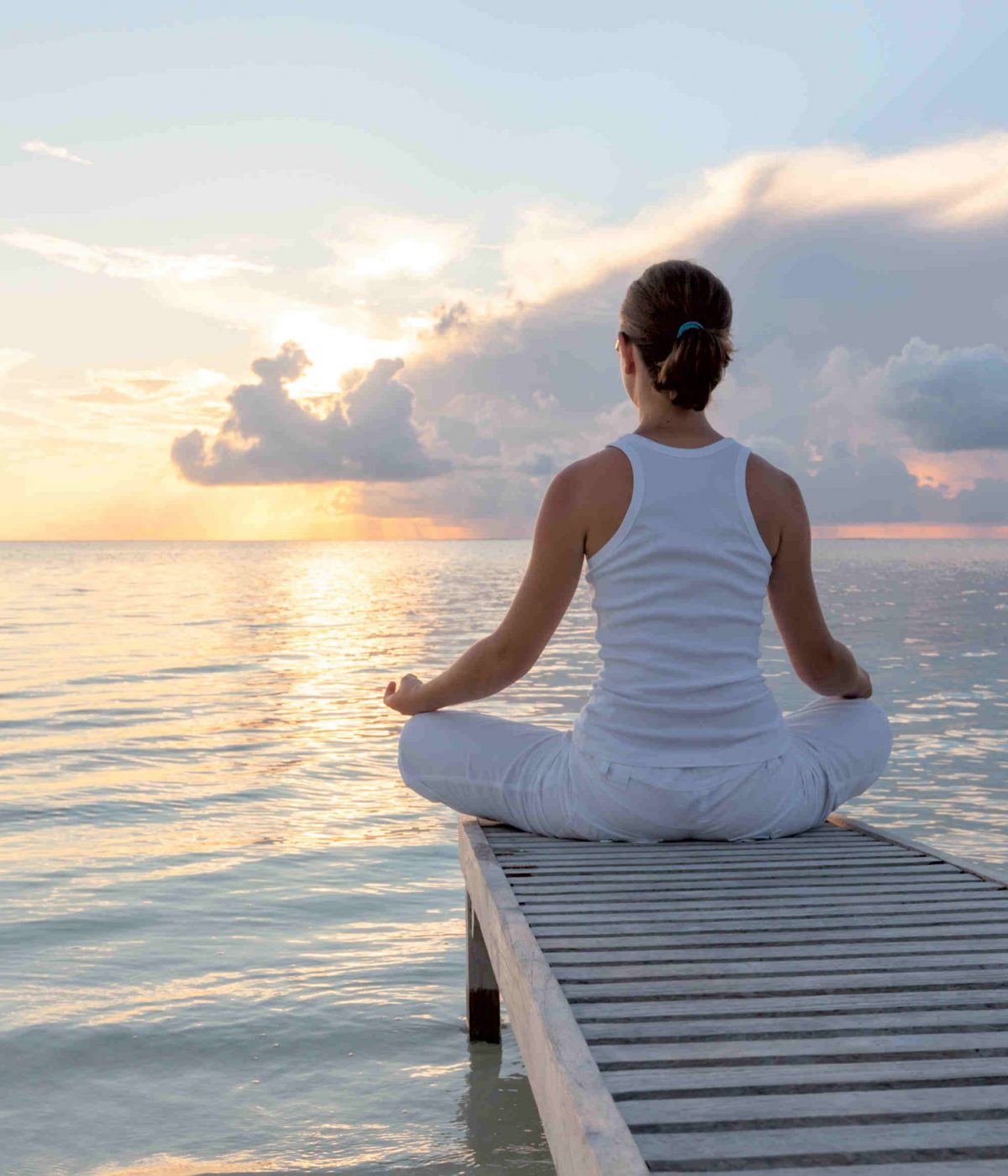 Caucasian woman practicing yoga at seashore in Maldives woman practicing yoga after RESTORE experience